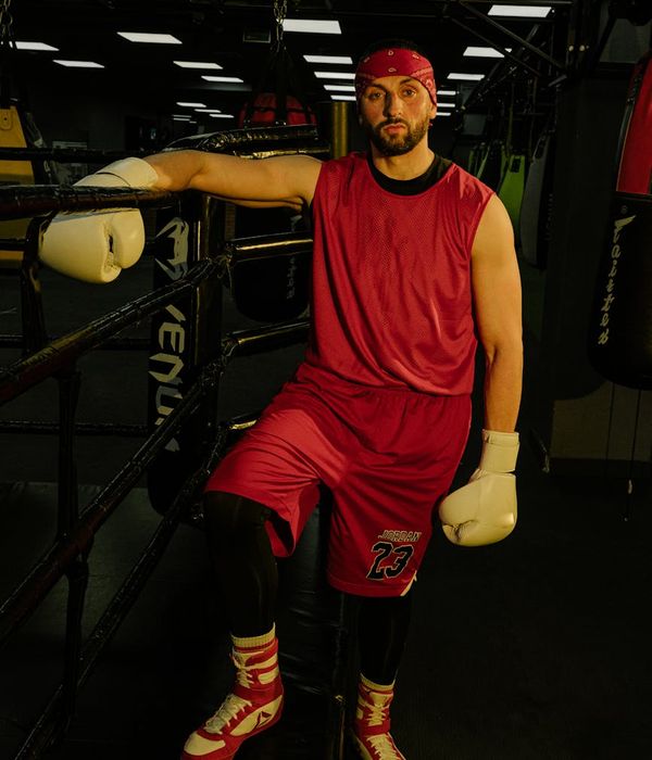 Man in a focused athletic stance in a dark gym environment.