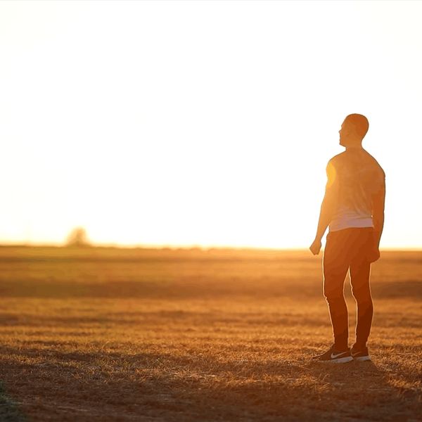 Silhouette of a man meditating against a sunrise background.
